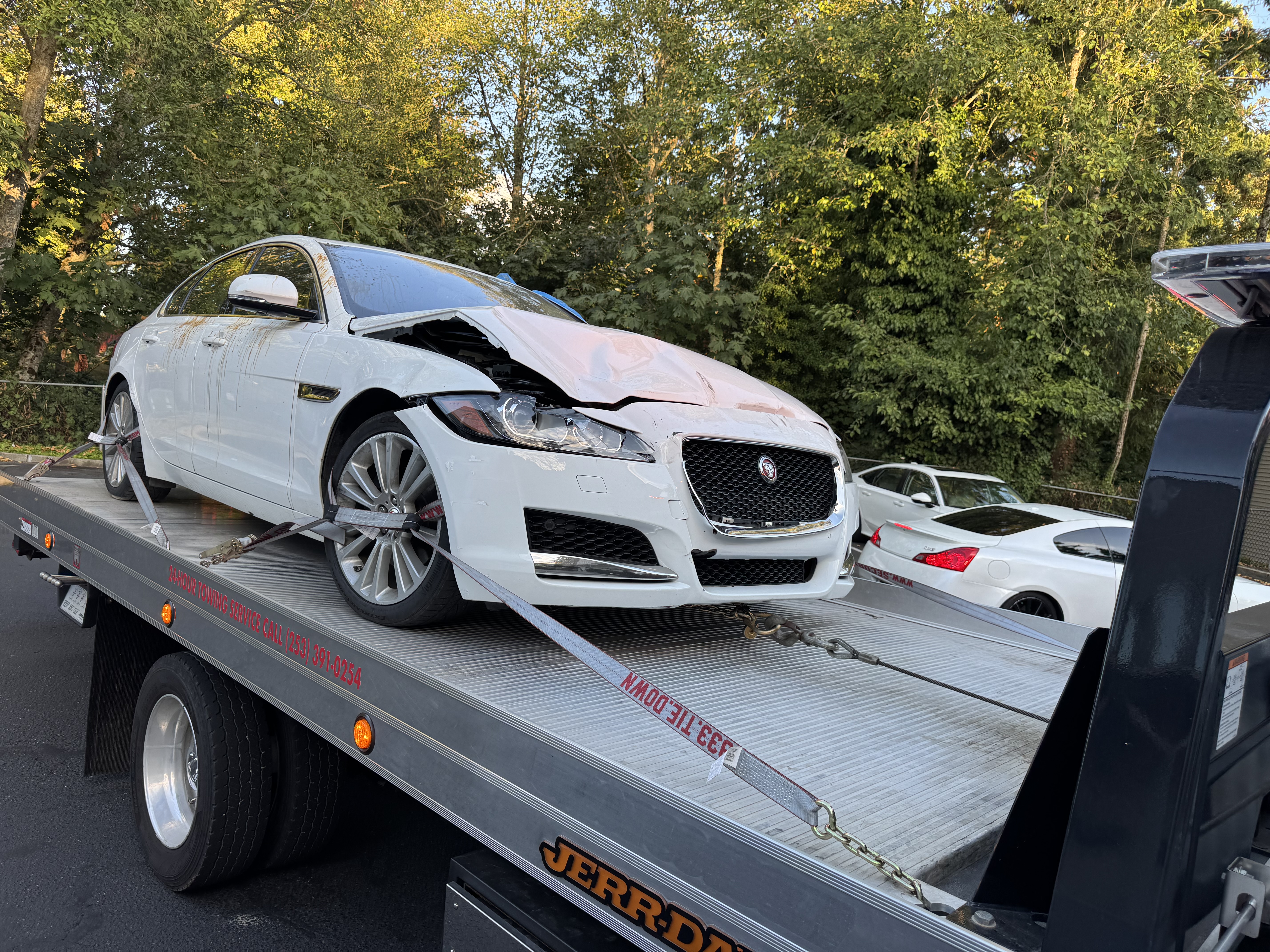 Collision-damaged white Jaguar secured on Pathfinder Towing's rollback