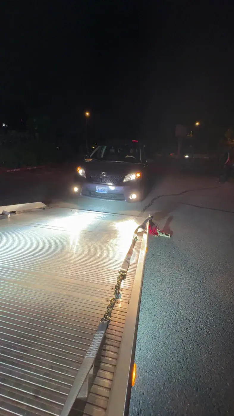 Vehicle being loaded onto an illuminated Pathfinder Towing flatbed at night