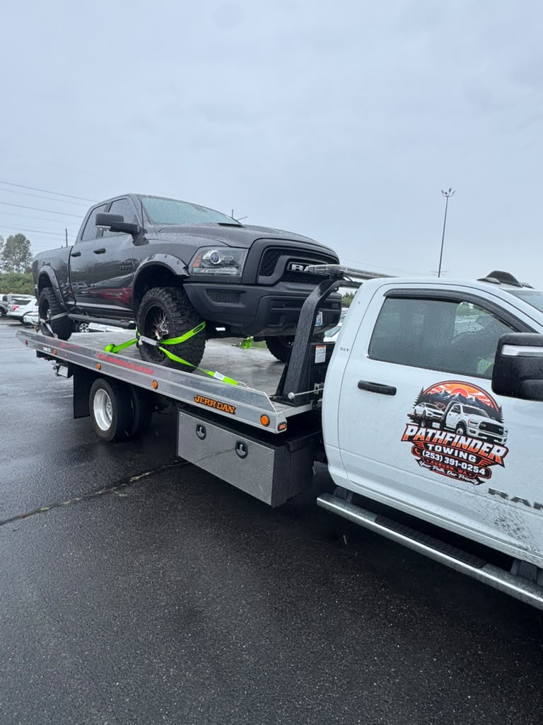 Pickup truck secured on Pathfinder Towing's rollback during rainy weather