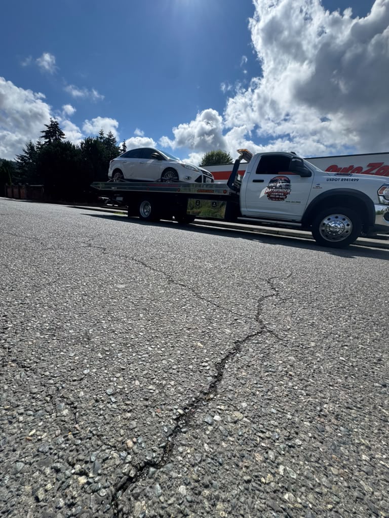 White Tesla transported on a Pathfinder Towing rollback flatbed